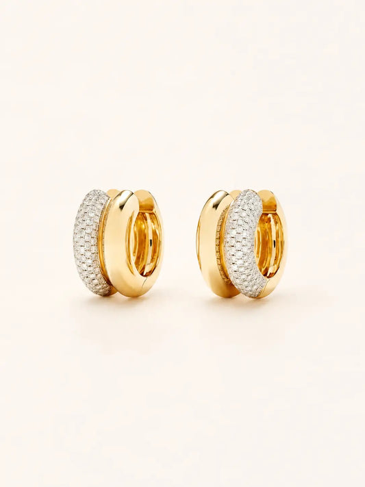 A pair of gold  hoop earrings with textured pavé-set clear stones on the front, photographed on a clean, light cream background.